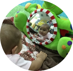 Baby looking at a mirror on teddy bear